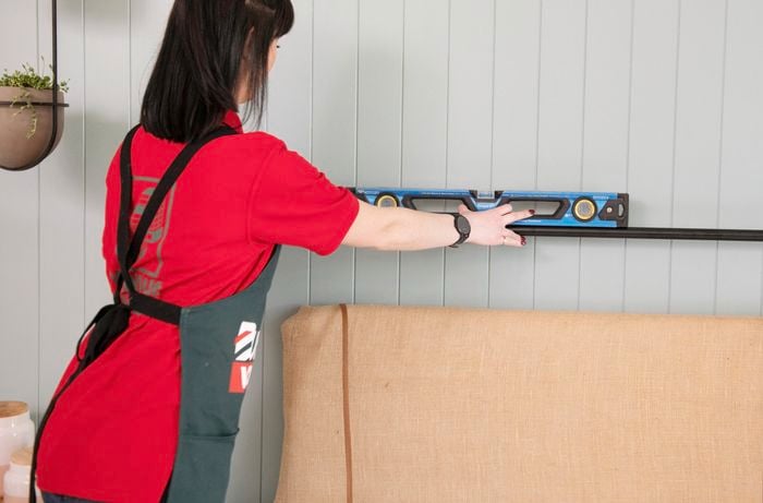 Person using spirit level on curtain rod to make sure it is sitting straight.
