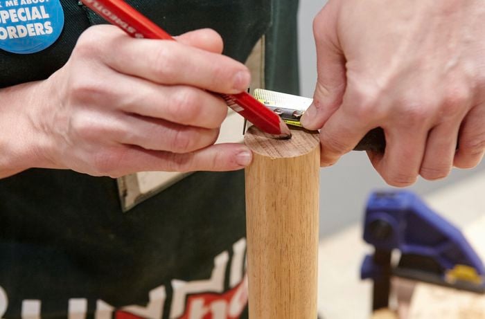 A person marking the centre of a piece of dowel