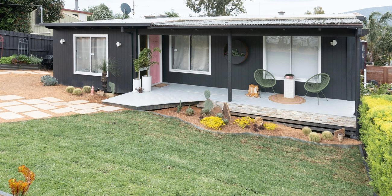 Front yard after transformation image of painted weatherboard house and manicured front lawn