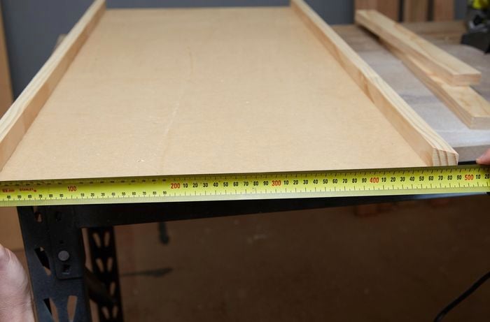 Person measuring piece of timber with tape measure