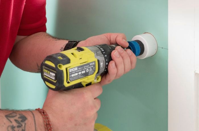 Drill a hole in the wall using a drill with a hole saw attachment 