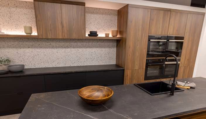 A kitchen with brown cupboards and a black marble benchtop in it.