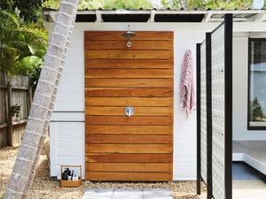 An outdoor shower with a timber slats and a white lattice panels