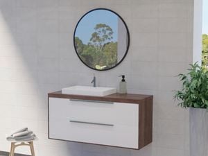 Bathroom with black framed mirror along with wash basin, plant and white wall tiles.
