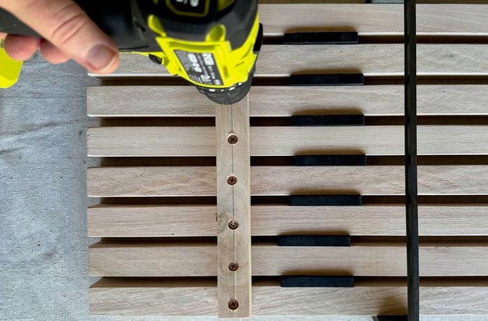 A hand drilling the rails together