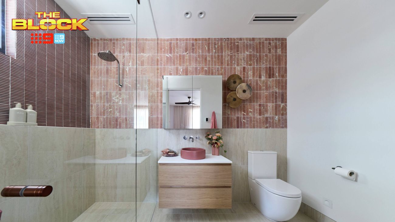 Contemporary ensuite featuring pink tiled walls, a walk-in shower, timber vanity and white toilet.