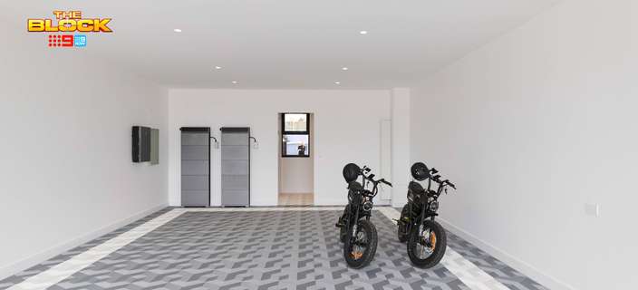 Modern garage featuring grey patterned floor tiles, white walls, two electric bikes and wall-mounted storage cabinets.