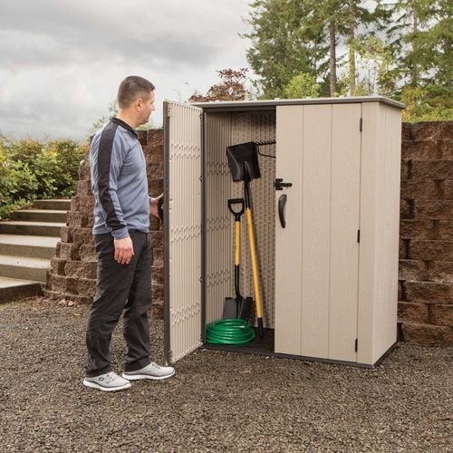 man looking inside garden shed with tools inside