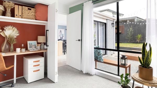 Home office with a concealed desk, filing drawer and indoor plants.