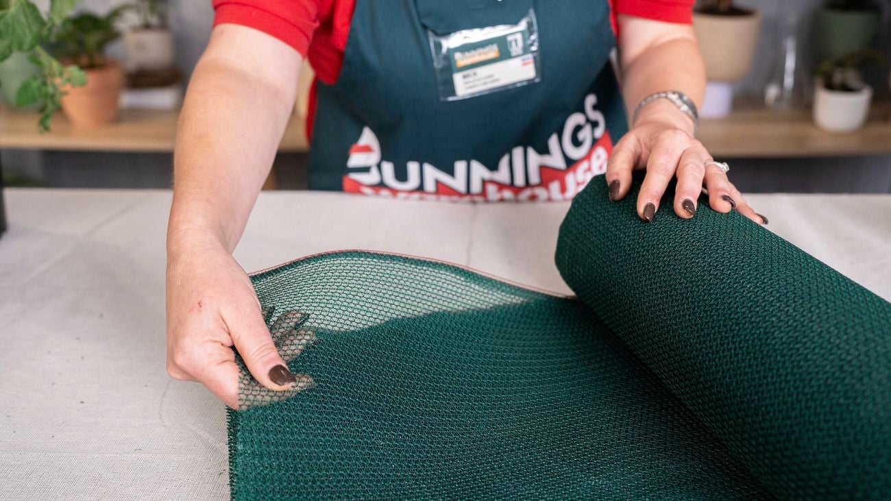 A Bunnings team member is holding sun shade cloth in their hand.