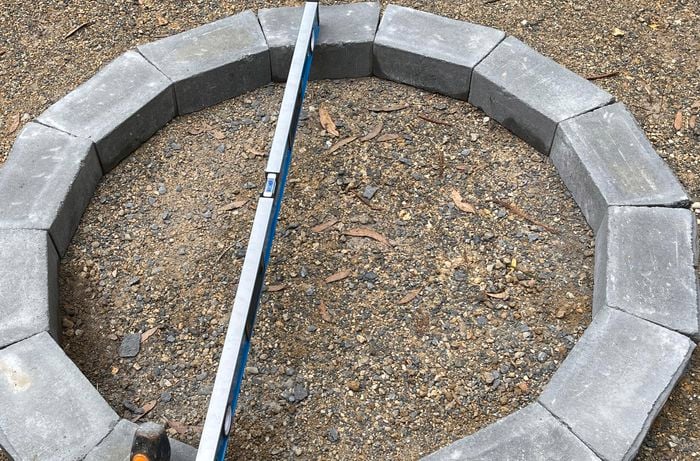 A person taps a hammer on retaining wall blocks to level them out