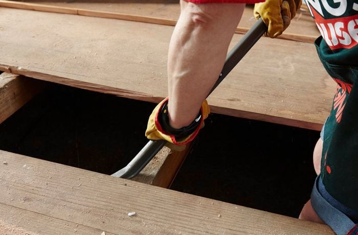 Close up of a Bunnings team member to pry up a floorboard using a crowbar