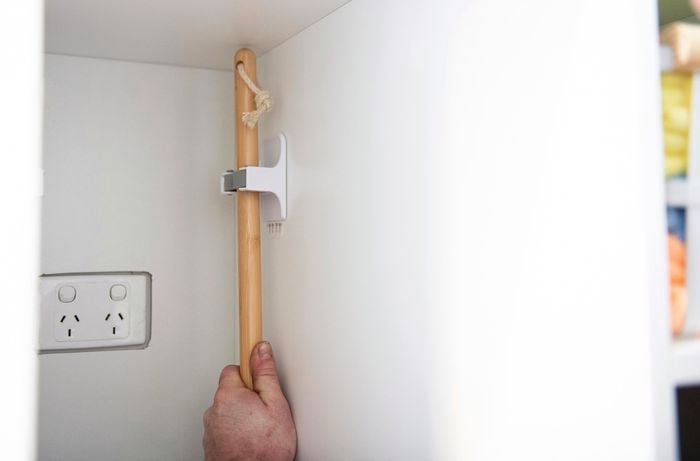 Person hanging broom in cupboard