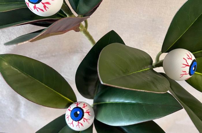 The flower buds from artificial magnolia greenery are removed by hand