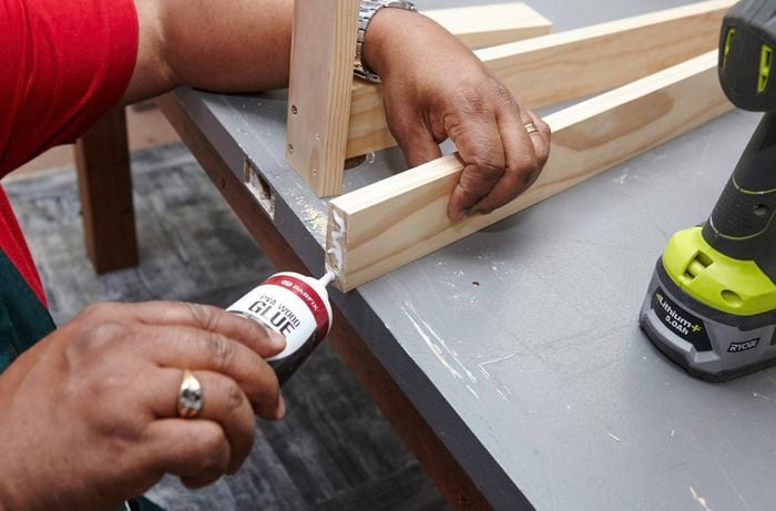A person applying glue to the end of a piece of timber