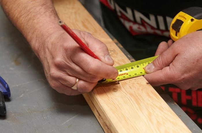 Person using tape measure and pencil to make a mark on timber.