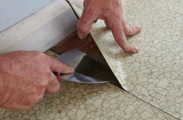Person prying vinyl flooring from the ground