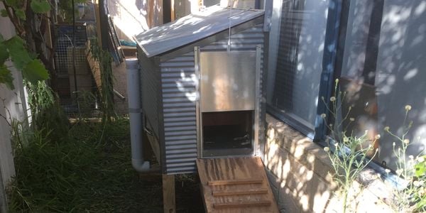 Chicken coop with a ramp attached to side of house