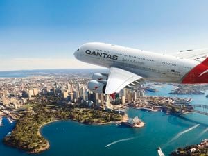 A Qantas plane in the sky amongst clouds.
