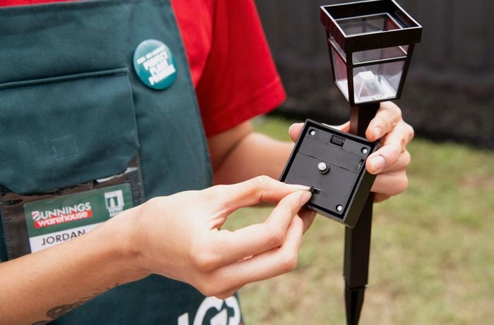 Person switching on a bollard garden solar light