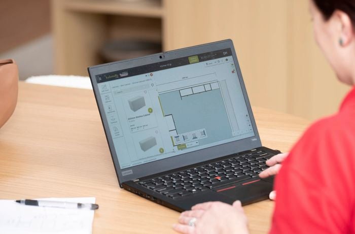 A person uses kitchen design software to plan cabinet and appliance layout for a functional, ergonomic kitchen. 