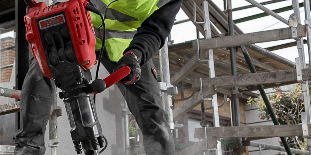 A workman holding a sledgehammer against the ground.