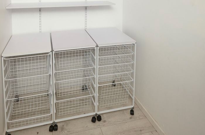 A linen closet with wire baskets trolleys