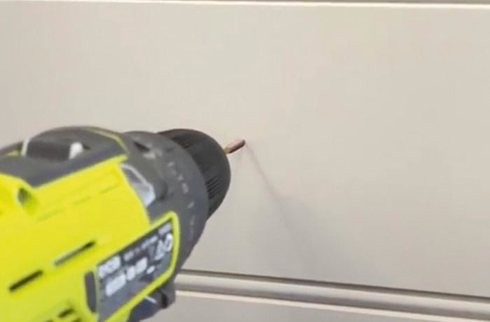 Hand drilling holes in wall.