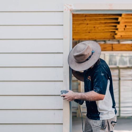 Person sanding a timber frame during construction