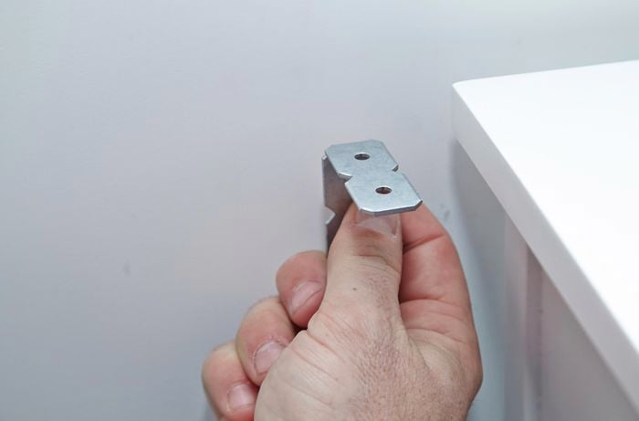 Person holding metal bracket.