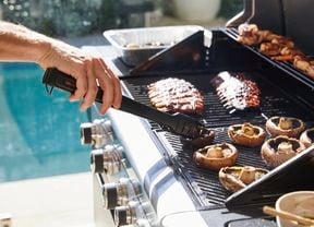 Barbecue in use with food being cooked for a family