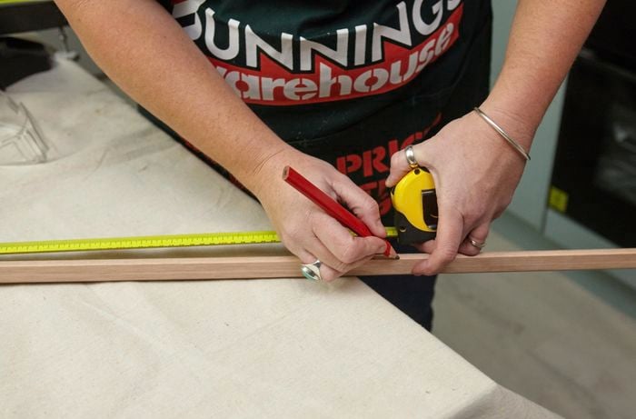 Person using measuring tape and pencil to mark up quad moulding.
