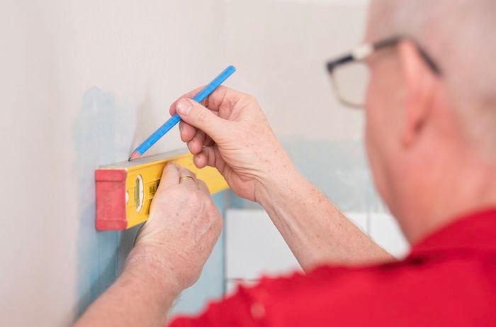 A person is choosing the tile trim pieces from a work surface that suit the project.  