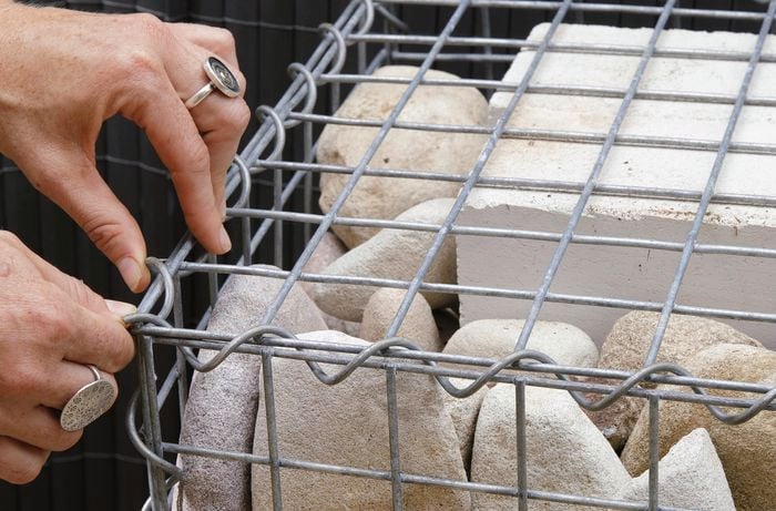 A gabion cage being secured with tie wire