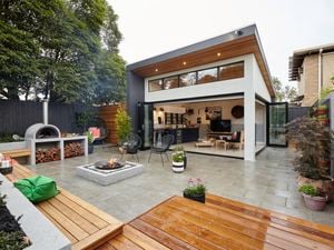 Modern house with open living area adjoining a paved outdoor entertaining area