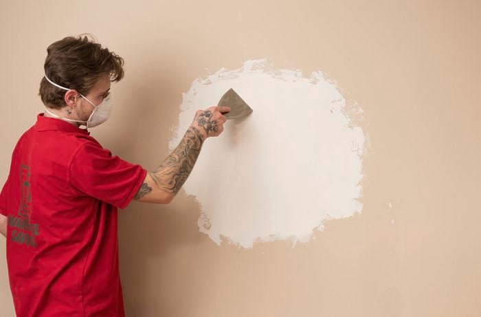 A Bunnings team member is applying a second coat to the plasterboard, blending it smoothly into the surrounding wall for a seamless finish