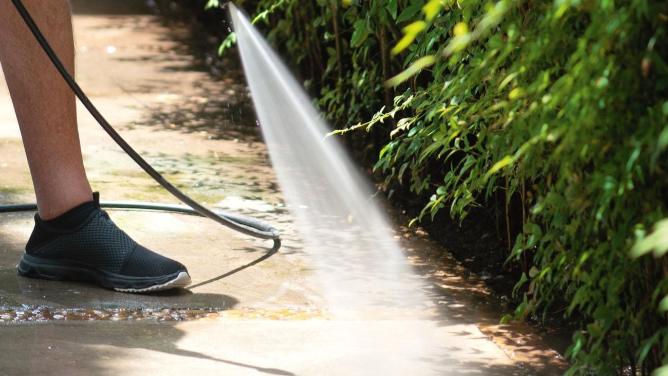 Man washing his concrete floor using a high pressure water cleaner