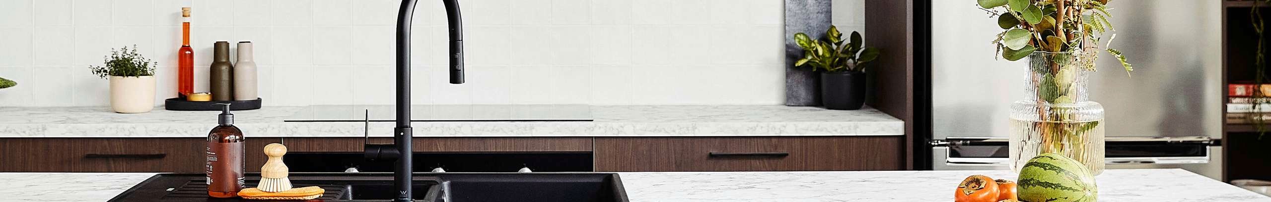 Brown modern kitchen with a white marble benchtop and back bar stools at the bench.