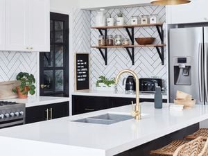 Kitchen with black cabinets and white benchtops.