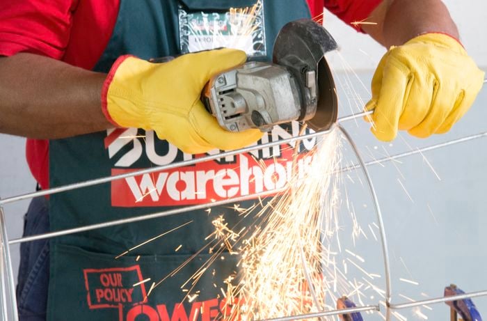 Person using angle grinder to cut trellis metal rods