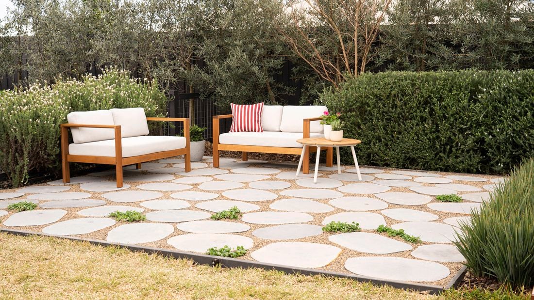 An outdoor patio showcases stepping stones with pebbles and greenery in between to fill the gaps