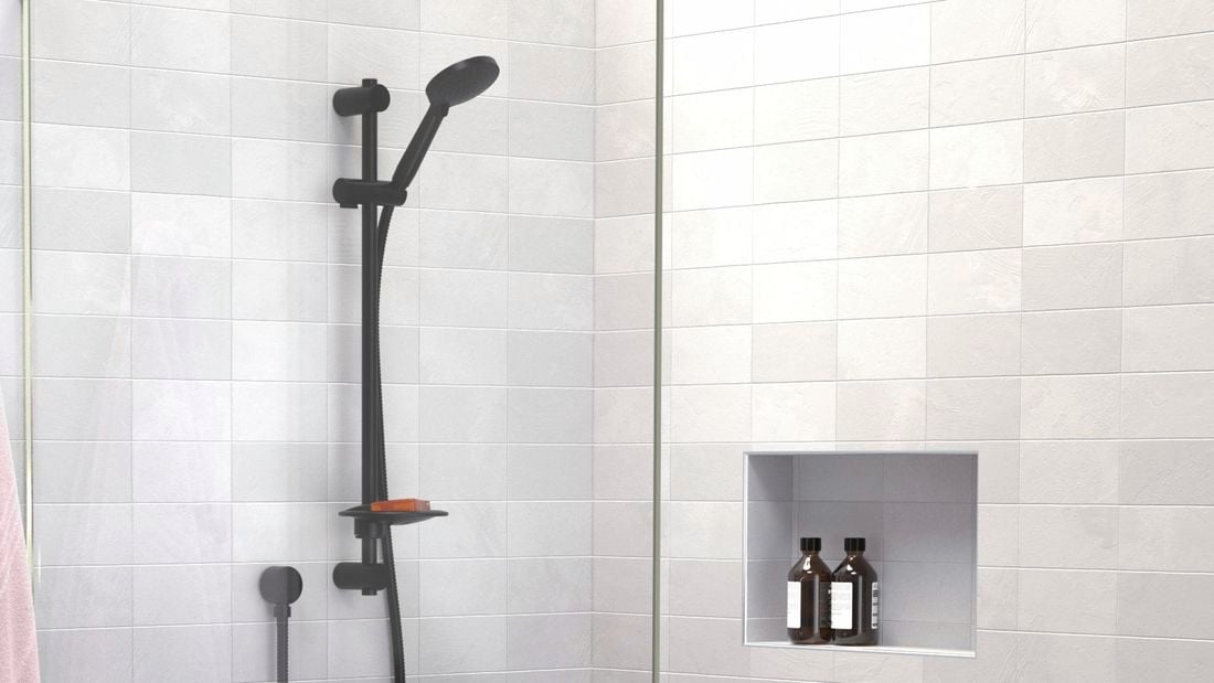 Bathroom with grey tiles, black tapware and pink towel hanging up.
