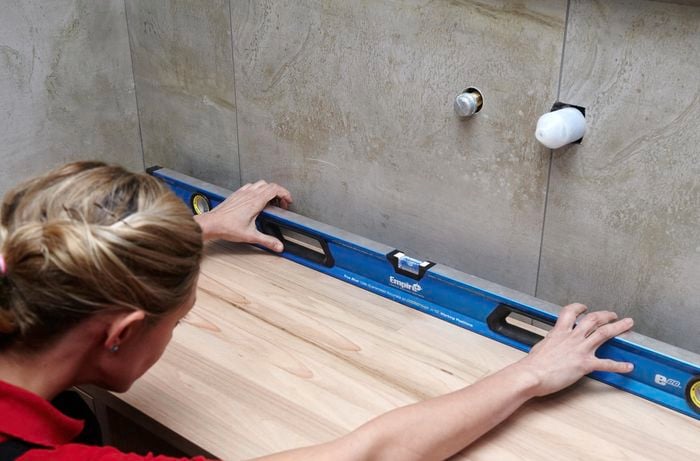 A person checking a timber vanity alignment with a spirit level