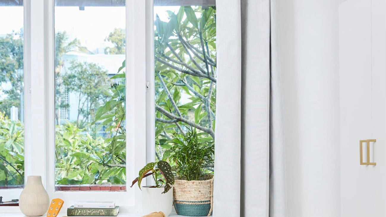 Close up shot of white curtains hanging open at a window.