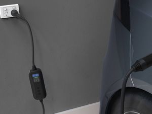 A Deta portable electric vehicle charger model with screen plugged into a car