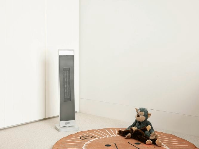 A room with a heater and two monkey bears on the floor in it.