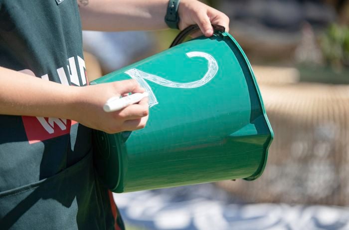 Person writing the number 2 on a bucket.
