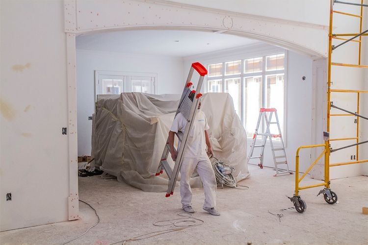 Painter carrying ladder under their arm in home