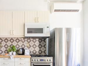 White kitchen with stainless steel appliances and overhead air conditioning unit