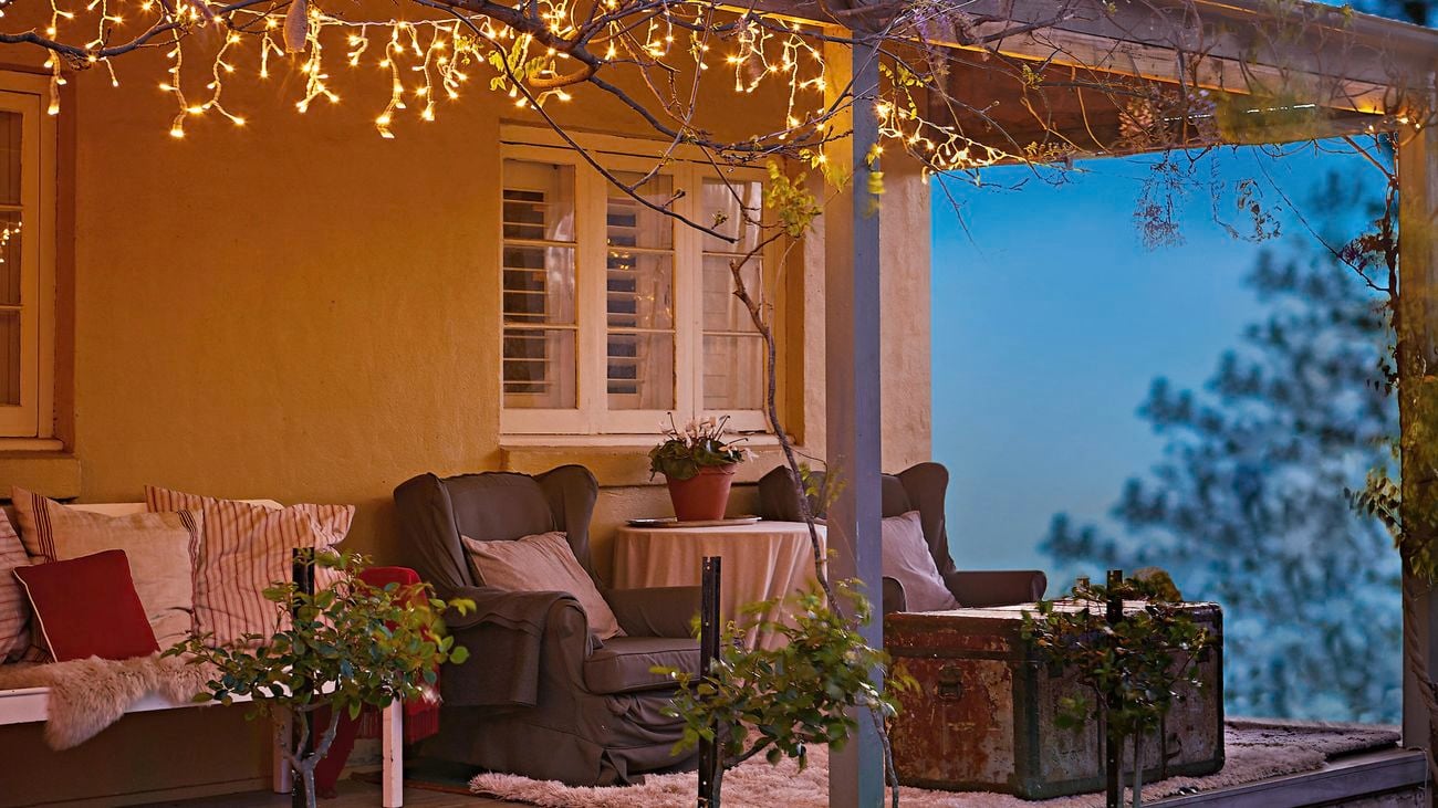 A string of fairy lights and stake lights in front of an old style house at night